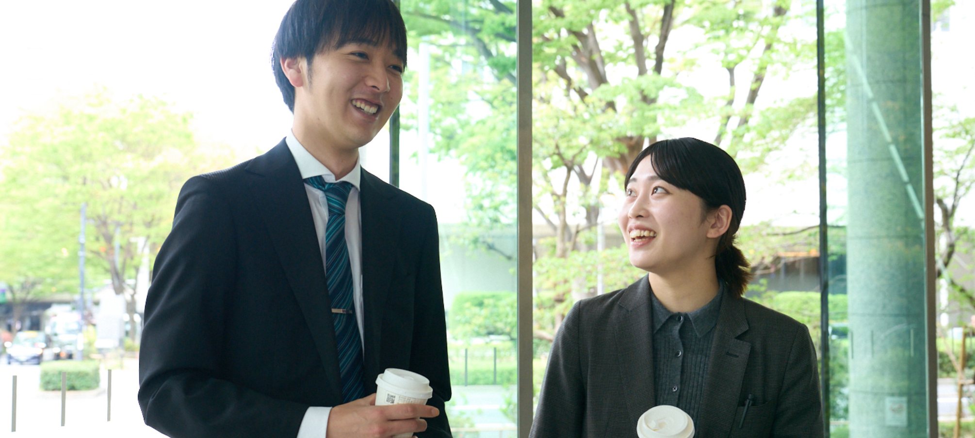 コーヒーを片手に談笑する男性・女性社員