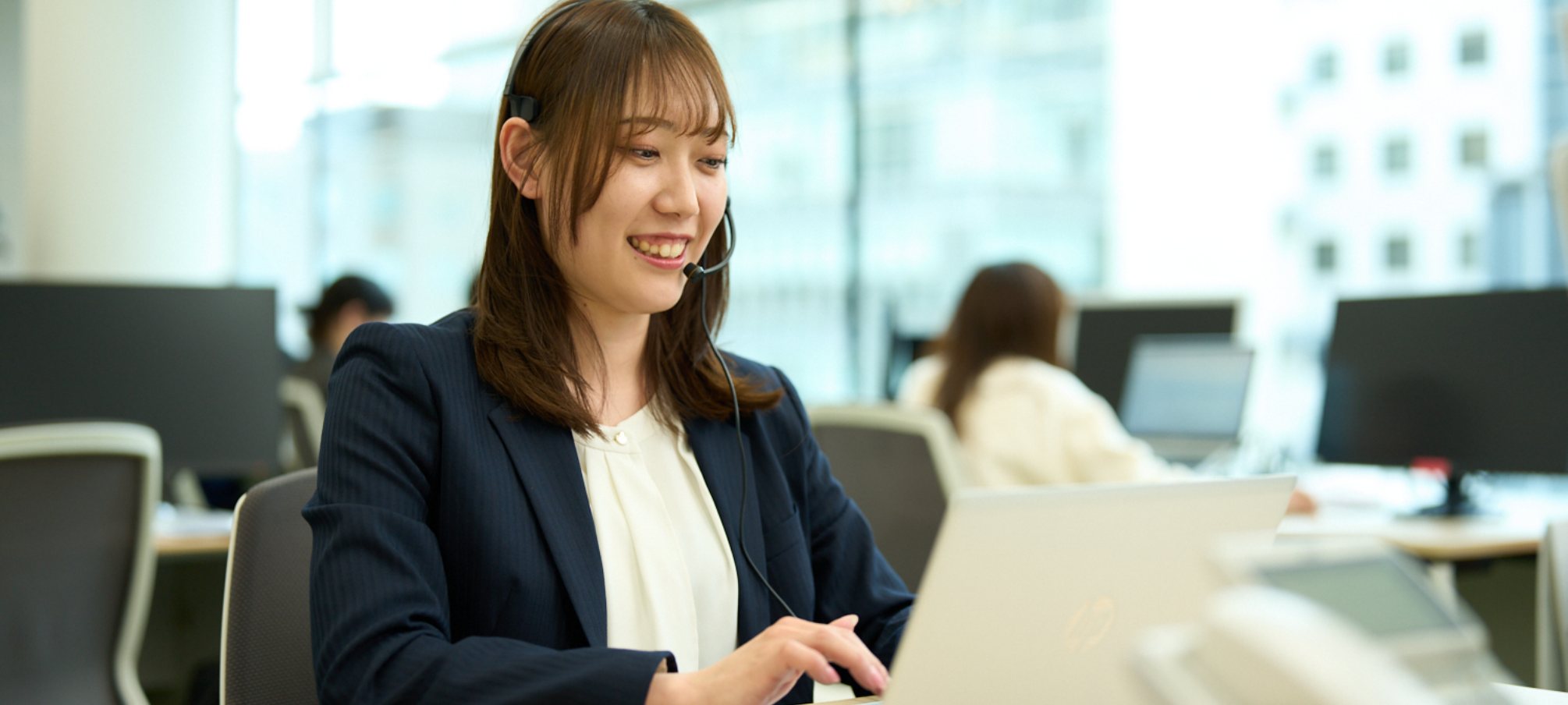 ヘッドセットをつけパソコンに向かう女性社員