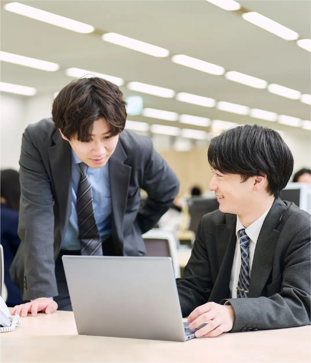 パソコンを見ながら話す2人の社員